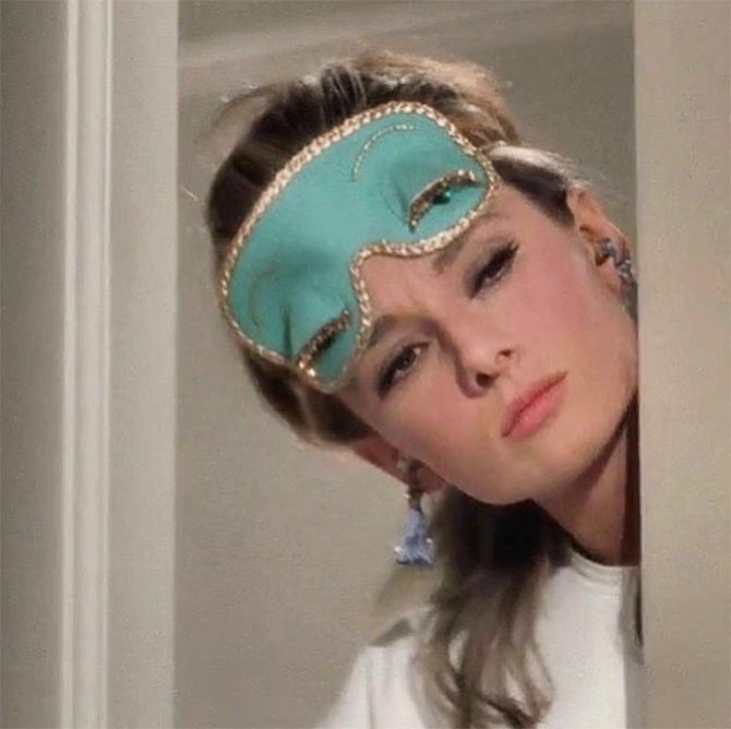 Audrey Hepburn wearing her Tiffany Blue colored sleeping mask and fringed ear plugs answers the door to meet her new neighbor in a scene from 'Breakfast at Tiffany's' (1961). 