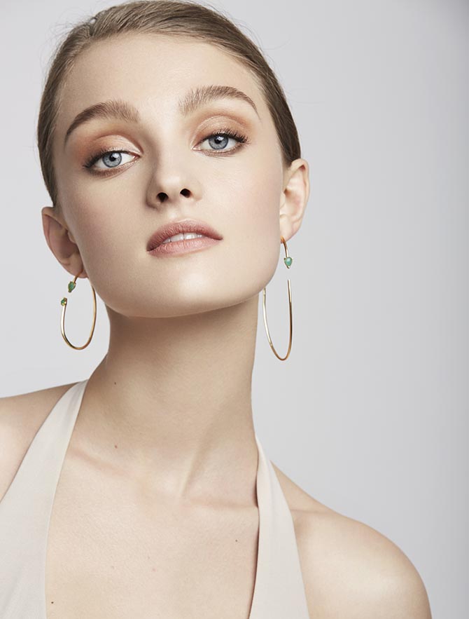 A model wearing emerald hoop earrings from Paige Novick's Powerful Pretty Things collection. Photo courtesy