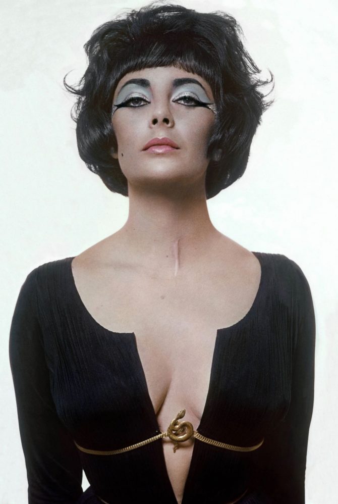 Elizabeth Taylor dressed as 'Cleopatra' in a shoot for Vogue with Bert Stern to publicize the movie wearing a black Fortuny pleated dress with a plunging neckline and a serpent clasp. Photo Bert Stern/Getty