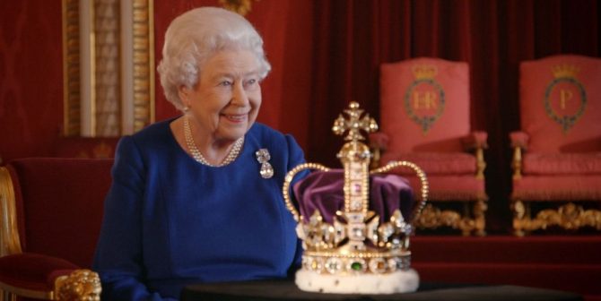 Queen Elizabeth wearing the Cullinan brooch with pearls seated behind St Edward's Crown in 'The Coronation.' 