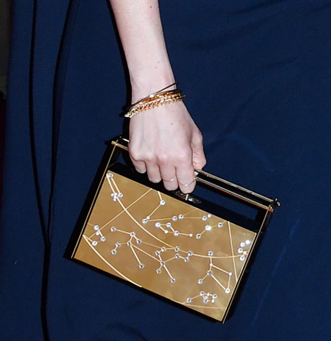 Detail of Meghan Markle carrying a Naeem Khan clutch bag and wearing Shaun Leane jewelry for Queen's 92nd birthday concert at Royal Albert Hall. Photo Getty Images