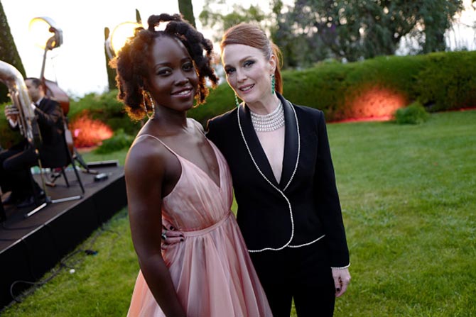 Lupita Nyong'o in a Prada dress and Chopard hoops poses with Julianne Moore in a Sonia Rykiel suit, emerald earrings and a diamond bib necklace from Chopard.