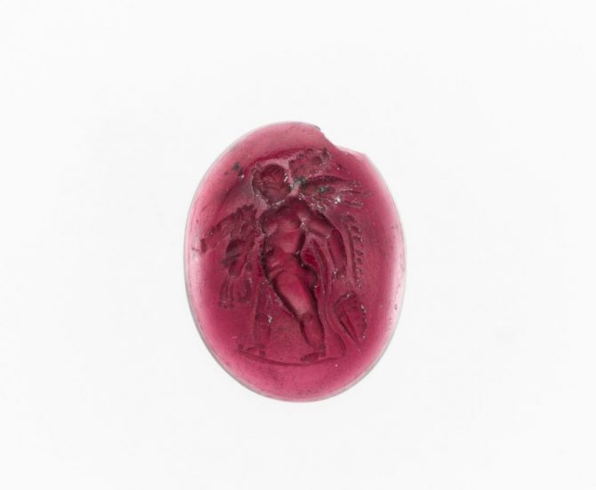 An almandine garnet intaglio dating from the Hellenistic period in Greece, around the 1st century BC features Eros walking and proudly carrying off the weapons of Herakles: the lion's skin, club, bow, and the quiver. Photo The MET