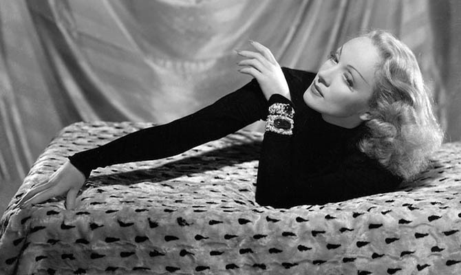Marlene Dietrich wearing her Trabert & Hoeffer-Mauboussin diamond bracelet set with a 127-carat cabochon emerald and her Paul Flato diamond bracelet set with an emerald cabochon in a film still by Clarence Sinclair Bull.
