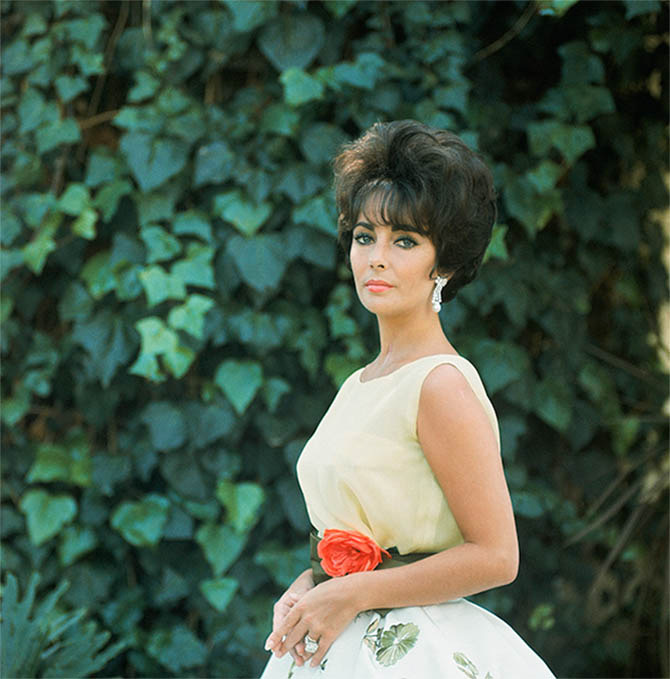 Elizabeth Taylor posed for lensman Mark Shaw in the Dior dress and Ruser diamond and pearl earrings, she wore when she won the 1961 Oscar. Photo via
